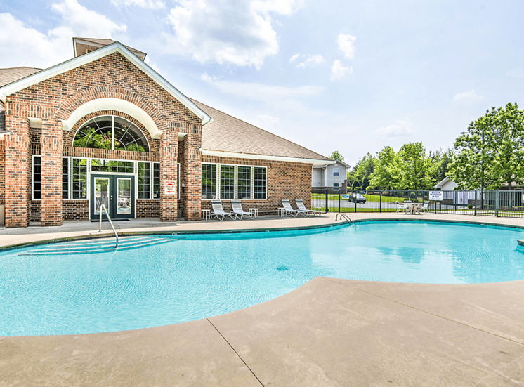 Leasing Office Exterior with Swimming Pool and Sun Deck with Lounge Chairs Near Tree-line